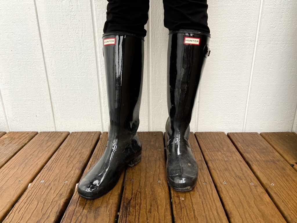 Glossy black rain boots against a white background, perfect to wear when visiting Astoria, Oregon.
