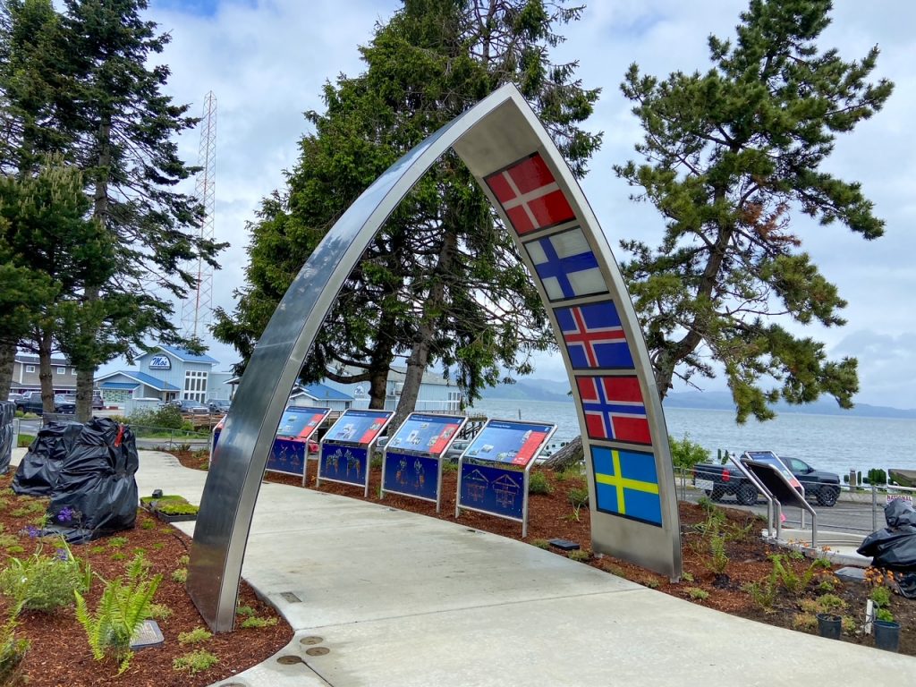 Arch shaped like the bow of a boat, featuring several Nordic flags at Nordic Heritage Park, one of the free things to do in Astoria, Oregon.