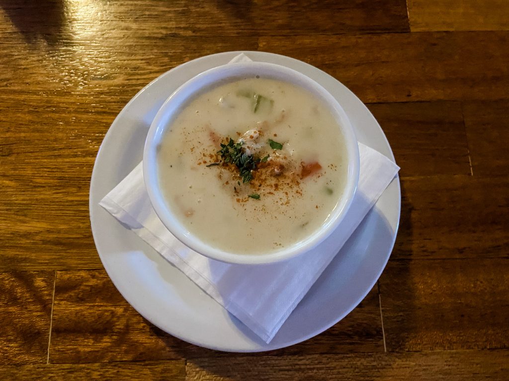 Cup of creamy clam chowder against a wooden table background.
