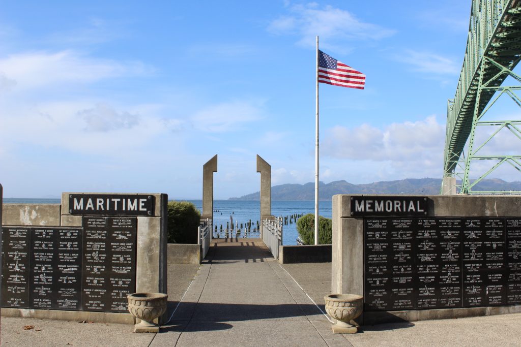 The Maritime Memorial in Astoria, Oregon sits on the bank of the Columbia River, with the Astoria-Megler Bridge running overhead.