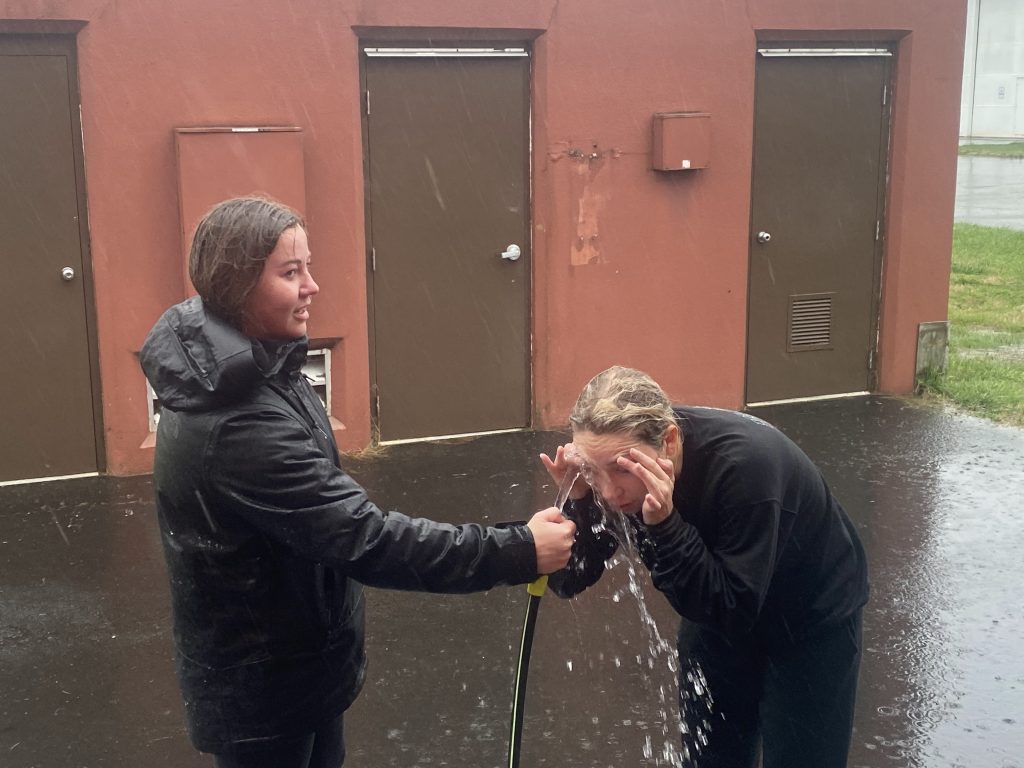 One woman holds a hose as another uses the water to flush out her eyes after getting pepper sprayed for training.